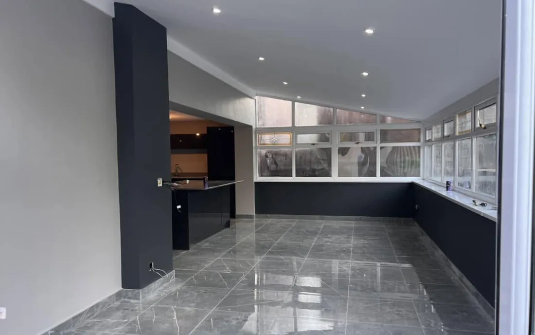 Open-plan kitchen and dining room in Caerphilly completed by LFB Contractors, with polished grey tiled floor and charcoal feature walls