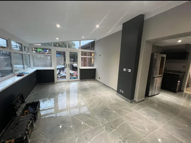Finished open-plan living space in Caerphilly with polished grey tiled floor and a charcoal feature wall